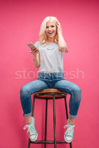 Cheerful woman sitting on the chair and listening music  Stock photo © deandrobot