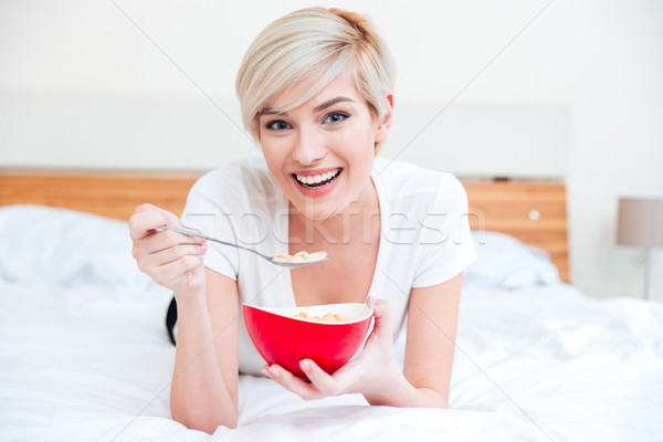Glimlachende vrouw eten granen bed naar camera Stockfoto © deandrobot