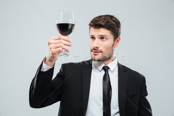 Serious man sommelier in suite tasting red wine in glass Stock photo © deandrobot