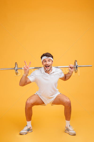 Funny sportsman doing squats with barbell and showing peace sign Stock photo © deandrobot
