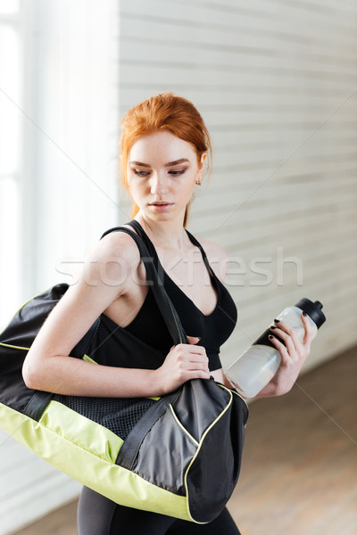 Young woman with bottle of water and sports bag Stock photo © deandrobot