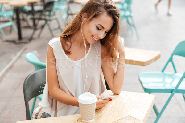 Woman with earphones listen music and typing message on smartphone Stock photo © deandrobot