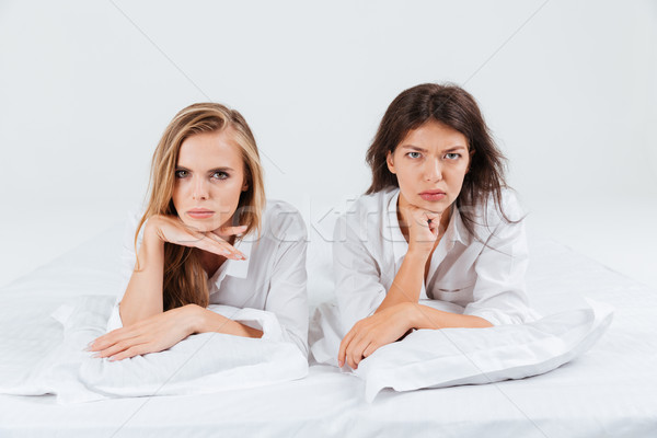 Two upset unhappy women lying together in bed Stock photo © deandrobot