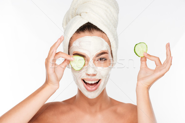 Stock photo: Woman with facial mask and cucumber slices in her hands