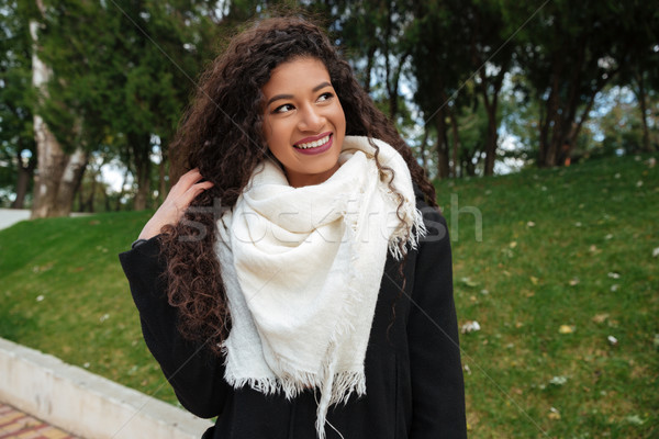 Beautiful african lady wearing scarf touching hair and look aside Stock photo © deandrobot