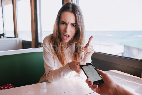 Displeased woman on date with her man which using phone Stock photo © deandrobot