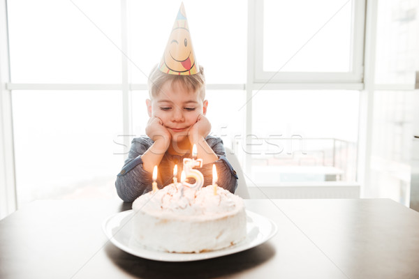 Dreaming birthday boy sitting in kitchen near cake Stock photo © deandrobot