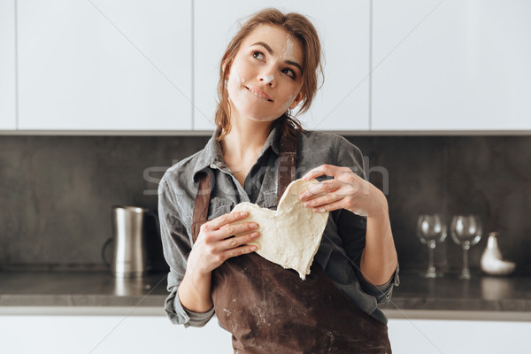 Thoughtful woman holding the dough heart. Stock photo © deandrobot