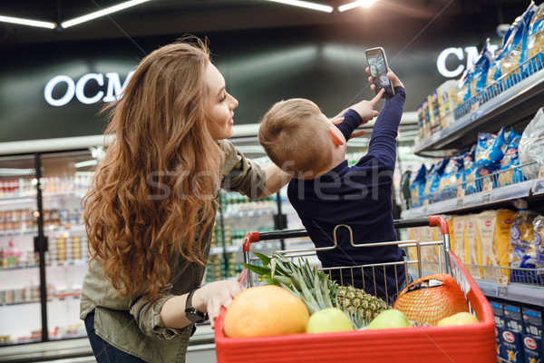 Back view of young boy making selfie with mom Stock photo © deandrobot