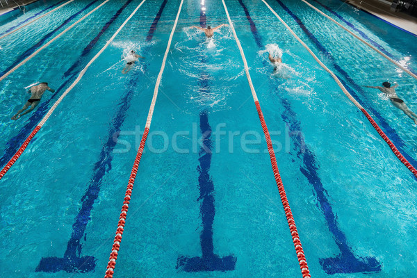 Five swimmers racing against each other in a swiming pool Stock photo © deandrobot