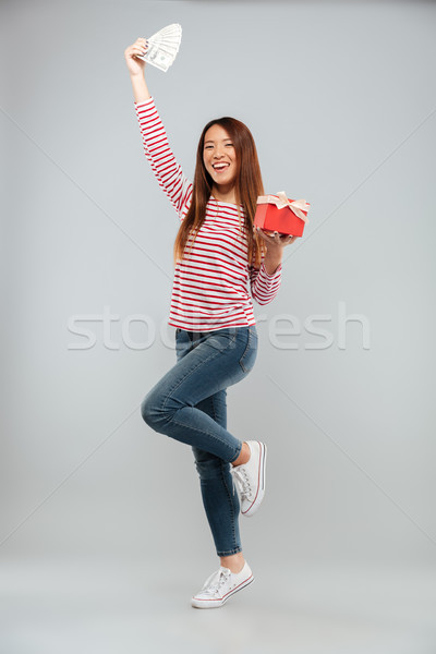 Amazing emotional young asian lady holding gift and money. Stock photo © deandrobot