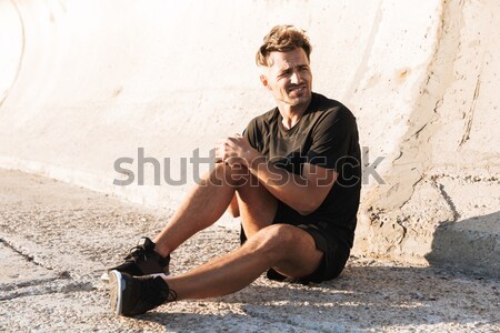 Portrait of an injured sportsman suffering from knee pain Stock photo © deandrobot