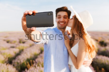 Photo of joyous young man and woman taking selfie, while walking Stock photo © deandrobot