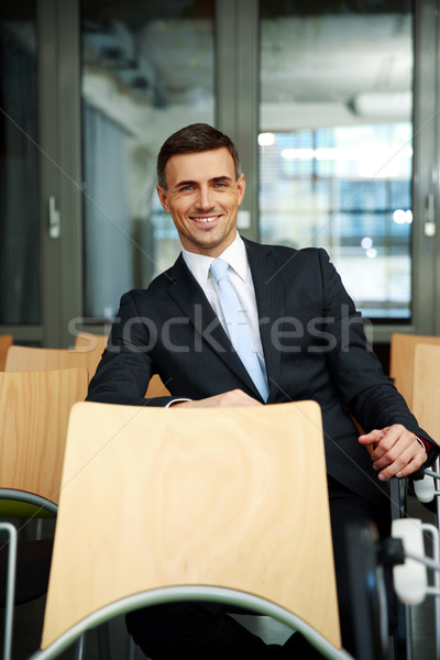 Smiling businessman sitting at conference hall Stock photo © deandrobot