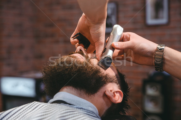 Young bearded man during beard grooming in barber shop Stock photo © deandrobot