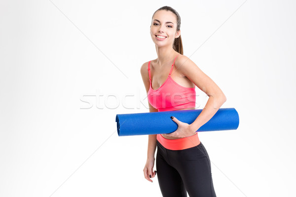Attractive cheerful young sportswoman holding yoga mat Stock photo © deandrobot