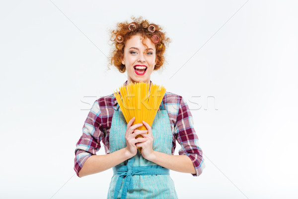 Happy housewife standing and holding uncooked spagetti  Stock photo © deandrobot