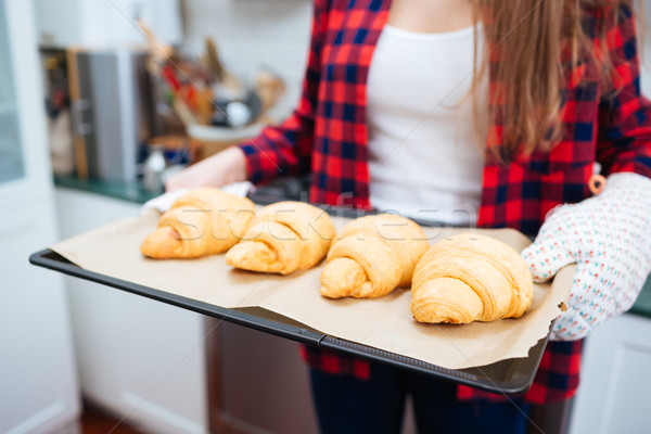 Young woman in gloves holding tray with croissants Stock photo © deandrobot