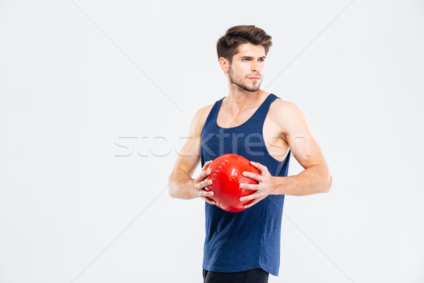 Concentrated young man athlete diong exercises with red ball Stock photo © deandrobot