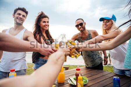 Happy young friends dringking beer and celebrating outdoors Stock photo © deandrobot