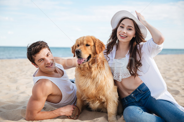 Happy smiling couple in love sitting on beach with dog Stock photo © deandrobot