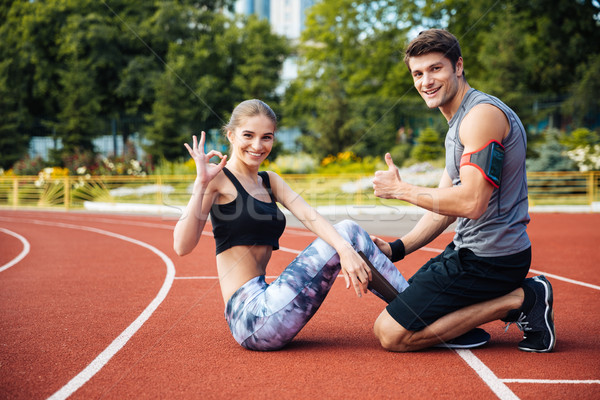 Young beautiful happy couple doing sports exercises at the stadium Stock photo © deandrobot