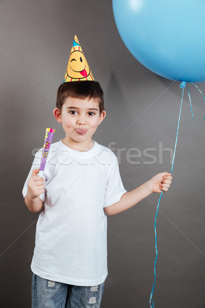 Little boy in birthday hat showing toungue and celebrating Stock photo © deandrobot