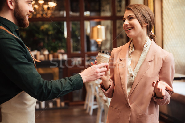 Stock photo: Attractive young man waiter standing in cafe gives the coffee