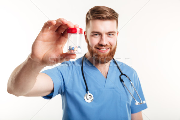 Portrait of a doctor holding up a bottle with tablets Stock photo © deandrobot