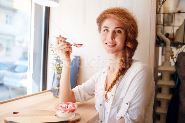 Smiling red haired woman sitting in cafe and eating dessert Stock photo © deandrobot