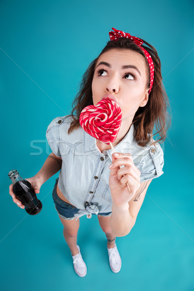 Serious woman standing isolated eating candy holding aerater sweet water. Stock photo © deandrobot