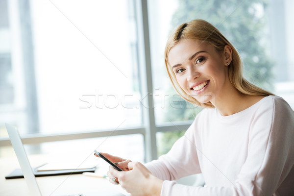 Cheerful lady sitting in office coworking chatting by phone. Stock photo © deandrobot