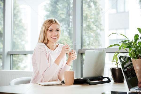 Happy lady sitting in office coworking while using laptop Stock photo © deandrobot