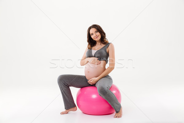 Smiling pregnant woman sitting on fitball and looking at camera Stock photo © deandrobot