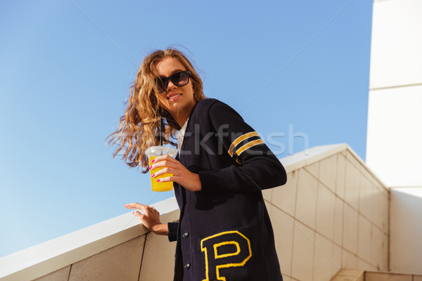 Smiling teenage girl in sunglasses drinking orange juice Stock photo © deandrobot