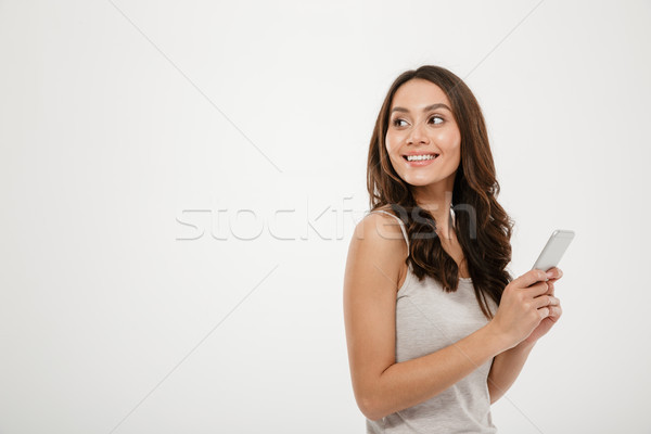 Side view of happy woman holding smartphone and looking back Stock photo © deandrobot