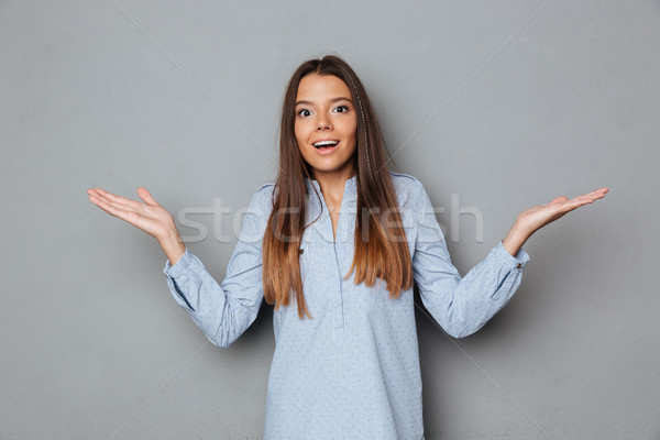 Happy surprised brunette woman in shirt shrugs her shoulder Stock photo © deandrobot