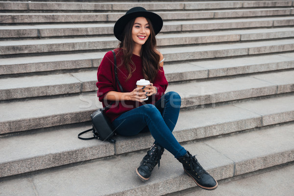 Smiling brunette woman in hat and sweater sitting on stairs Stock photo © deandrobot