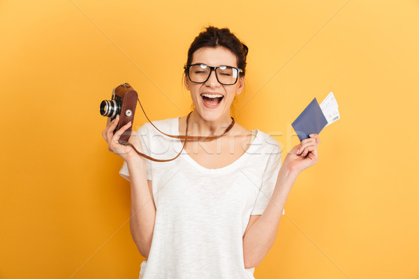 Young pretty woman tourist holding passport with tickets and camera. Stock photo © deandrobot