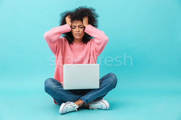 Photo of dissatisfied woman grabbing head and using silver noteb Stock photo © deandrobot