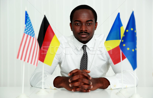 Serious african man sitting at the table in office Stock photo © deandrobot