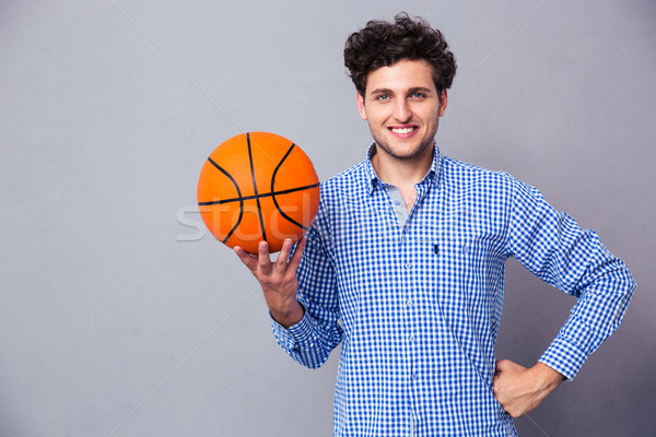 Smiling young man holding basket ball  Stock photo © deandrobot