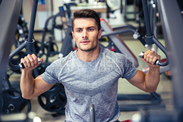 Bodybuilder workout on fitness machine at gym Stock photo © deandrobot