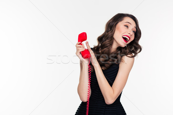 Happy attractive woman with retro hairstyle talking covering phone receiver  Stock photo © deandrobot