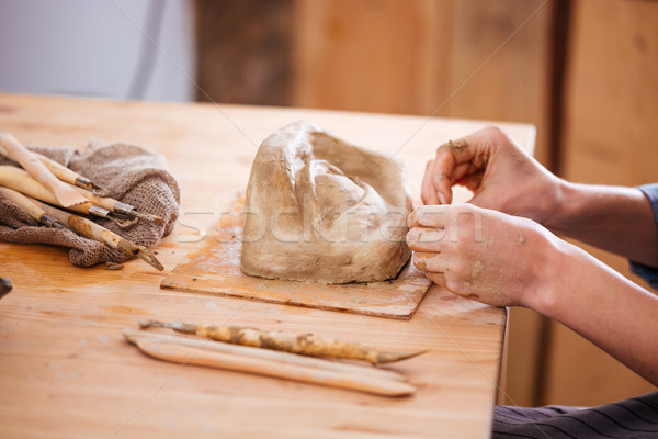 Stock photo: Hands of woman ceramist finishing sculpture with clay in workshop