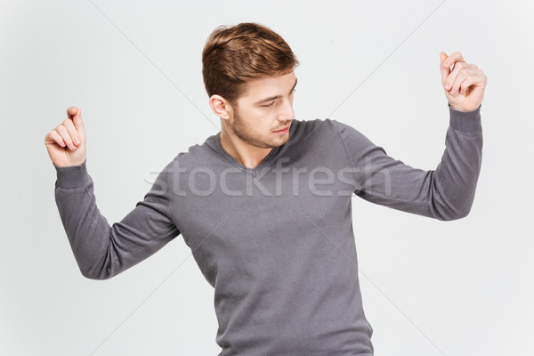 Handsome confident man in grey pullover dancing with raised hands Stock photo © deandrobot