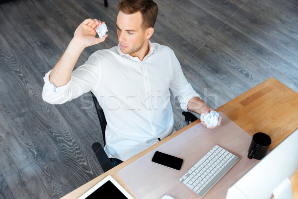 Serious businessman throwing crumpled paper and working in office Stock photo © deandrobot
