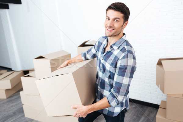 Happy man moving in and carrying carton boxes Stock photo © deandrobot