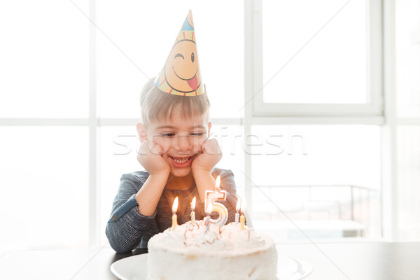 Joyful birthday boy sitting in kitchen near cake Stock photo © deandrobot