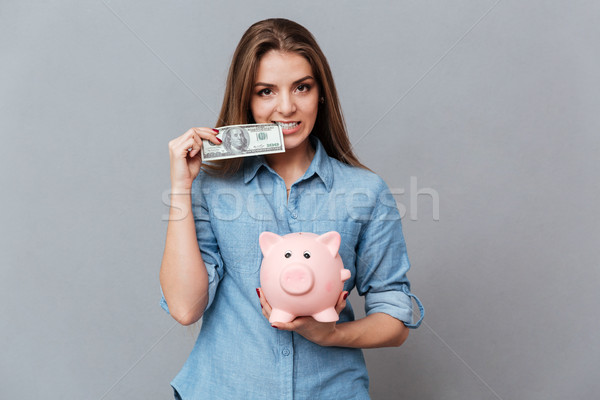 Woman in shirt holding moneybox and money in hands Stock photo © deandrobot